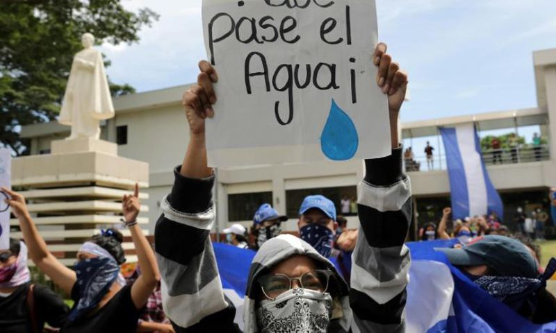 A student carries a sign reading "Let the water pass" during a protest of students and relatives of political prisoners, in Managua on Tuesday