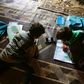 Young pupils follow a lesson on a mobile telephone at a camp for displaced Syrians in the village of Kafr Yahmoul in northwestern Idlib province