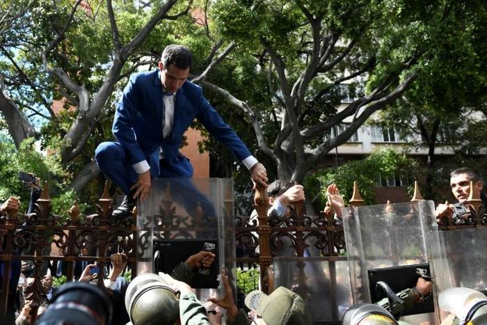 Venezuelan opposition leader and self-proclaimed acting president Juan Guaido is pushed back by police with riot shields as he tries access the National Assembly compound
