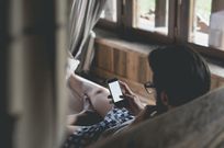 Young man using smartphone lying in bed at home