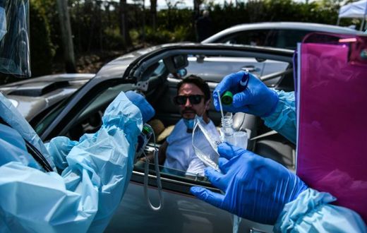 Health workers administer a test for coronavirus at a drive-through facility in West Palm Beach, Florida