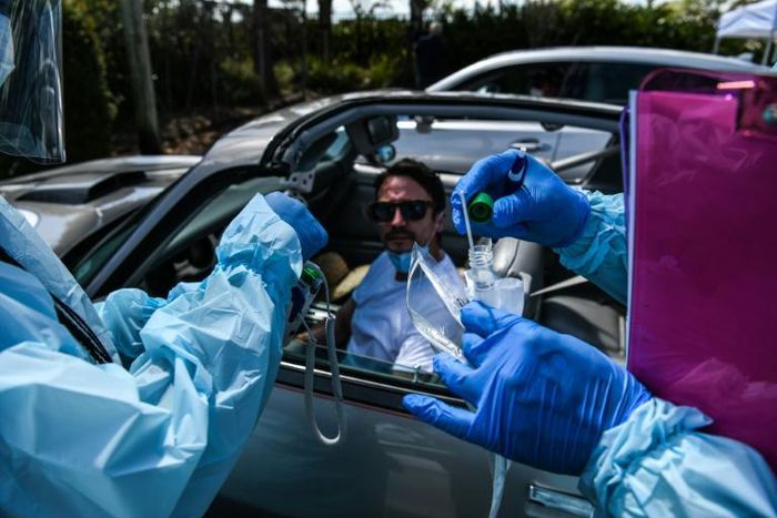 Health workers administer a test for coronavirus at a drive-through facility in West Palm Beach, Florida