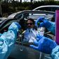 Health workers administer a test for coronavirus at a drive-through facility in West Palm Beach, Florida