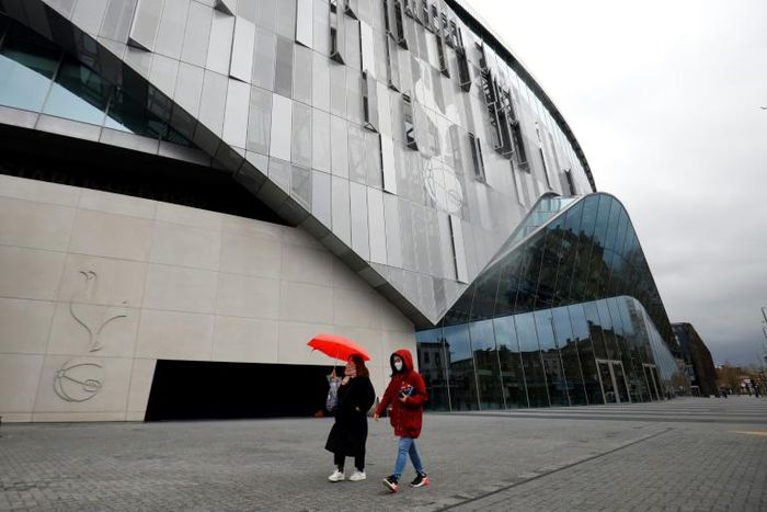 A woman wearing a protective face mask walks near the Tottenham Hotspur Stadium