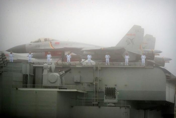 Sailors stand near fighter jets on the deck of the Chinese People's Liberation Army Navy aircraft carrier Liaoning