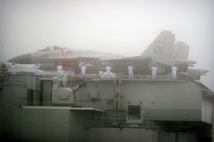 Sailors stand near fighter jets on the deck of the Chinese People's Liberation Army Navy aircraft carrier Liaoning
