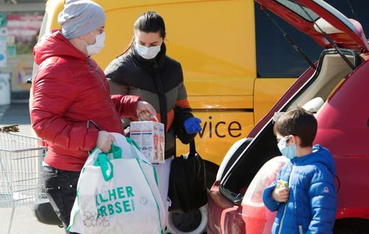 A family ensure they have their masks on as they put shopping in the car in Brunn am Gebirge near Vienna