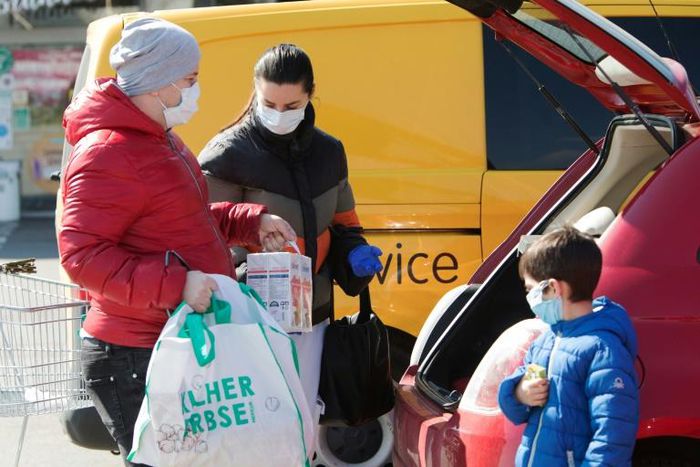 A family ensure they have their masks on as they put shopping in the car in Brunn am Gebirge near Vienna
