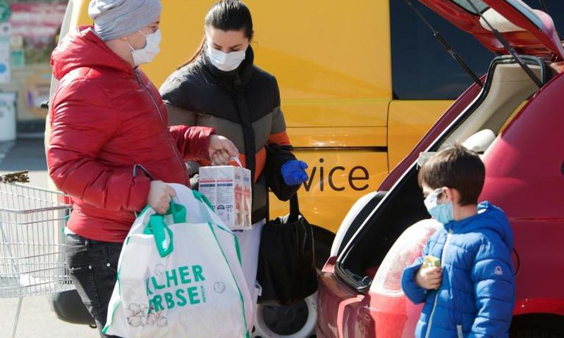 A family ensure they have their masks on as they put shopping in the car in Brunn am Gebirge near Vienna