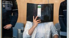 Defendant Sief Allah H. holds a folder in front of his face at the start of his trial on June 7, 2019 at a court in Duesseldorf, western Germany