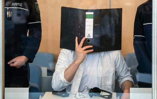 Defendant Sief Allah H. holds a folder in front of his face at the start of his trial on June 7, 2019 at a court in Duesseldorf, western Germany