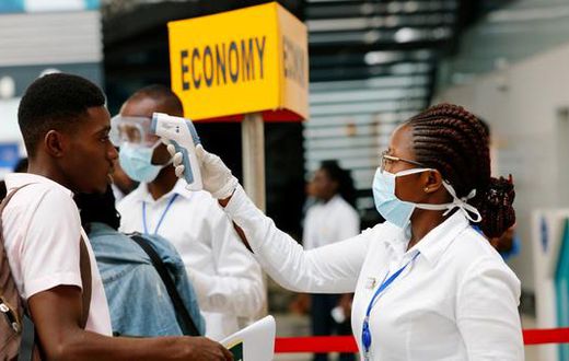 A health worker checks temperature of traveller as part of Coronavirus screening procedure at the Kotoka International Airport