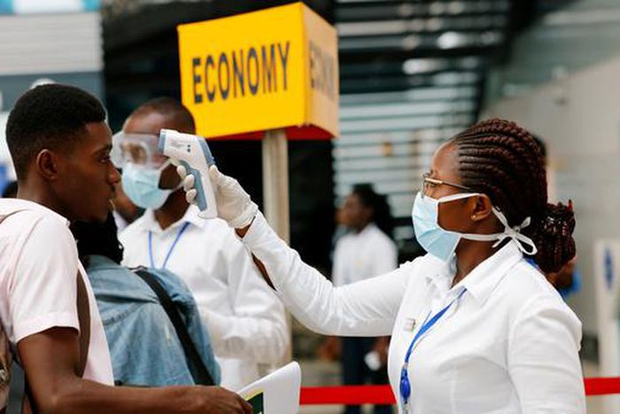 A health worker checks temperature of traveller as part of Coronavirus screening procedure at the Kotoka International Airport