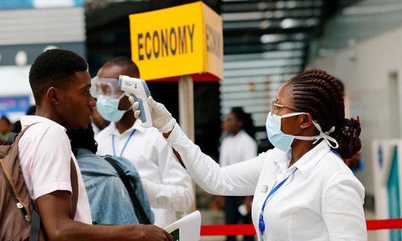 A health worker checks temperature of traveller as part of Coronavirus screening procedure at the Kotoka International Airport