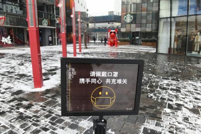 A sign urges visitors to wear face masks at the entrance to an empty shopping mall in Beijing