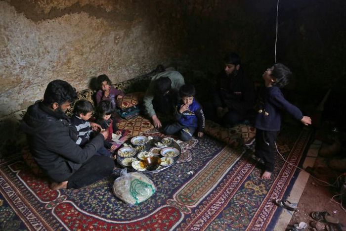 Darra lays down a large carpet for the family to share a frugal meal on the bare earth of the underground shelter