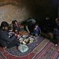 Darra lays down a large carpet for the family to share a frugal meal on the bare earth of the underground shelter