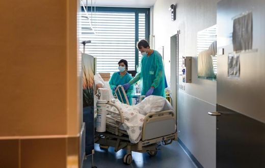 A Swiss soldier (R) helps to move the bed of a COVID-19 patient, at the Pourtales Hospital in Neuchatel on March 25, 2020, after Switzerland deployed its army reservists to relieve hospitals under pressure from the outbreak of COVID-19