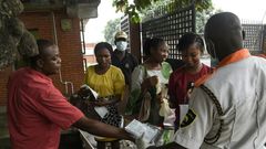Visitors to a state hospital in Lagos collect facemasks and gloves and have their hands sanitised