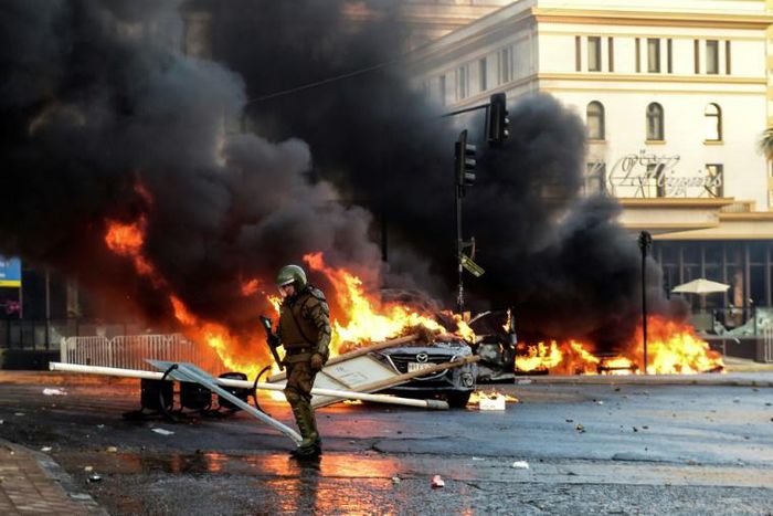 A policeman is seen near torched cars during a protest Sunday against Chilean President Sebastian Pinera's government in music festival venue Vina del Mar