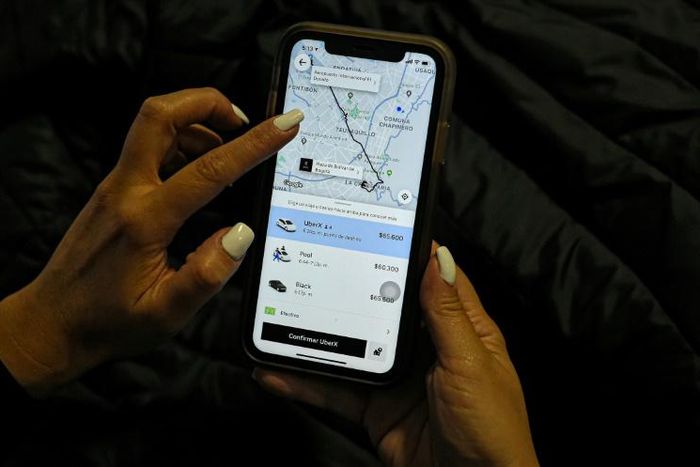 A woman checks the Uber transport application on her mobile phone after authorities ordered its suspension in Colombia, in Bogota on December 20, 2019