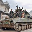 Syrian troops pass through a recaptured village in their final push on the strategic highway town of Maaret a-Numan, held by the rebels for seven years
