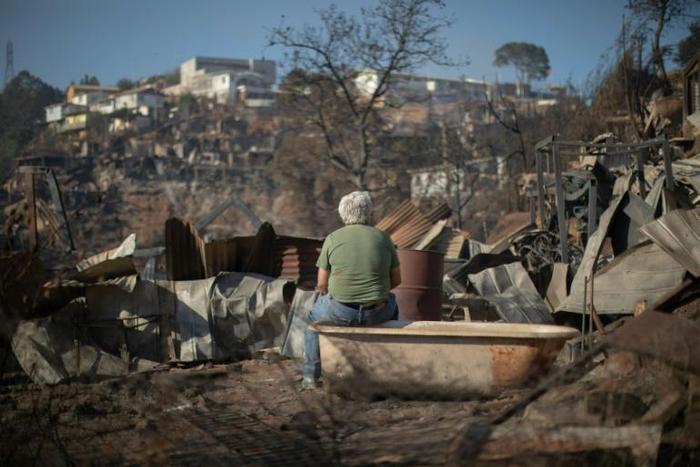 A man looks at the destruction caused by a forest fire on Rocuant hill in Valparaiso, Chile, on December 25, 2019