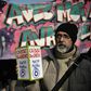 A protester holds a donation box for strikers in front of a banner portraying President Emmanuel Macron during a march against France's pension reform in Paris on Friday.