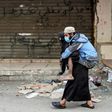 A woman carries a disabled man wearing a protective face mask in the Sabra refugee camp in Lebanon where vulnerable Syrian and Palestinian refugees are bracing for the coronavirus