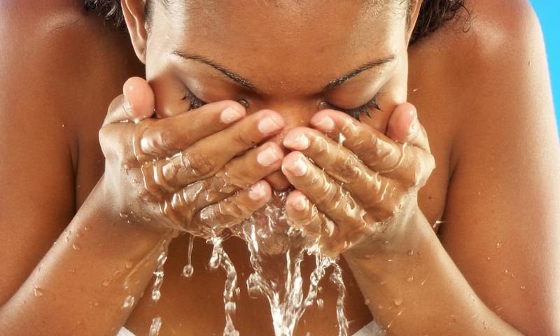African woman washing her face