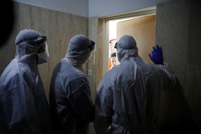 Health Ministry inspectors speak with a woman who is in self quarantine as a precaution against coronavirus spread in Hadera, Israel March 16, 2020 REUTERS/Ronen Zvulun