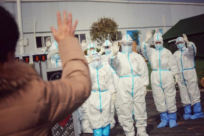 Medical staff members wave to a recovered patient at a makeshift hospital for the COVID-19 coronavirus patients in Wuhan