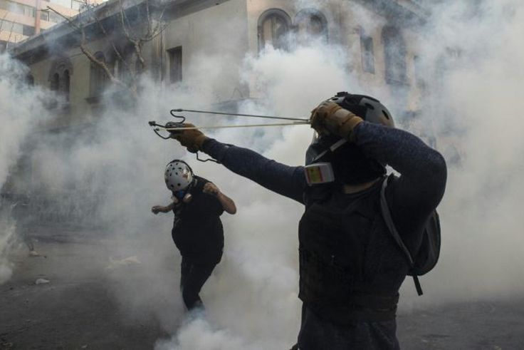 A demonstrator aims a sling at the police during a protest against Chilean President Sebastian Pinera's government in Santiago