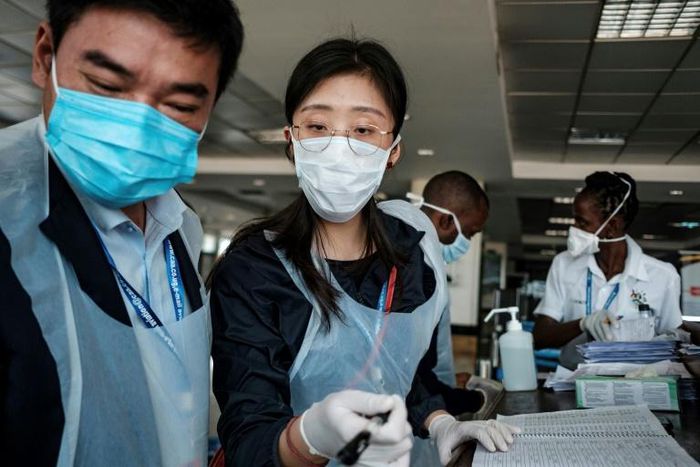 Chinese embassy officials help screen incoming passengers for the new coronavirus as they arrive at Entebbe Airport in Uganda on March 3, 2020