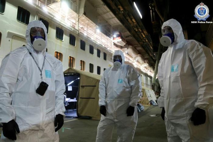 Police officers in protective gear prepare to board the coronavirus-stricken Ruby Princess cruise ship and seize its black box at Port Kembla, Australia