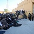 Iraqi security forces stand guard as protesters hold a prayer inside the walls of the US embassy in Baghdad's Green Zone