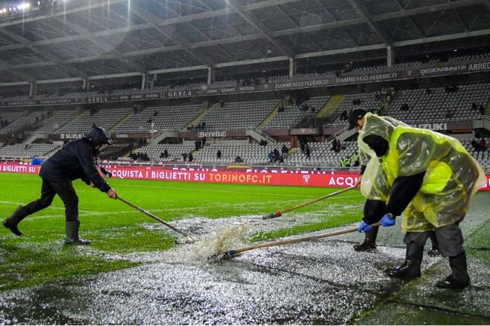 Groundsmen clear water from the pitch before the Torino v Inter Milan Serie A game in Turin