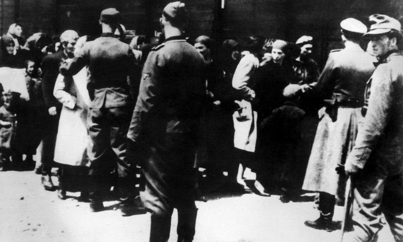 SS soldiers lead newly arrived prisoners to the gas chambers at the Auschwitz concentration camp. The death camp remains an enduring symbol of the Holocaust.