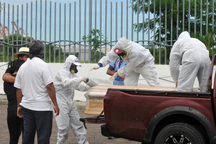 Workers wrap with plastic a coffin with the remains of a person who died from the coronavirus, COVID-19 in Guayaquil, Ecuador