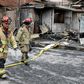 Firefighters walk past destroyed houses after the explosion of a gas tanker in Lima left at least eight people dead and dozens injured