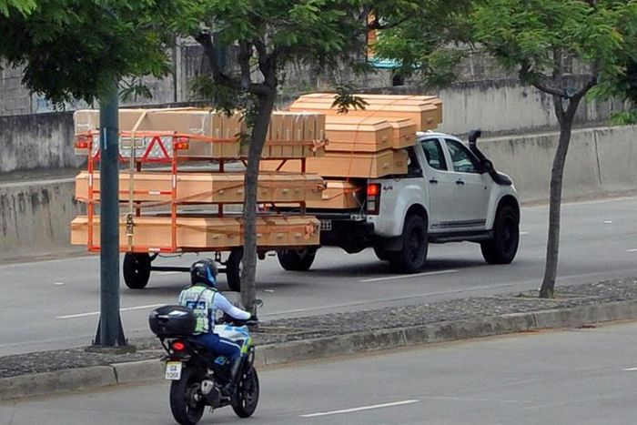 Coffins are seen stacked high on a pick-up truck and trailer as it passes a hospital in Guayaquil, Ecuador