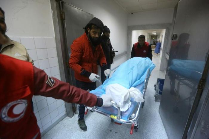 Emergency personnel pull a gurney with a victim on it from an air strike on a military school in the capital Tripoli