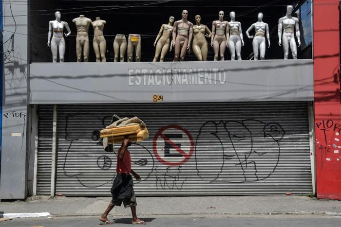 A homeless walks past a closed parking lot and mannequins in downtown Sao Paulo, Brazil, after the city government decreed the closure of shops and stores as a precautionary measure against the spread of the novel coronavirus COVID-19, on March 24, 202...