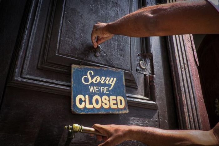 An employee of Havana's El Cafe coffee shop puts up a sign that has become a familiar sight during the coronavirus pandemic