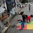 Children play near their families' tents set up on a street outside Eleonas refugee camp in Athens