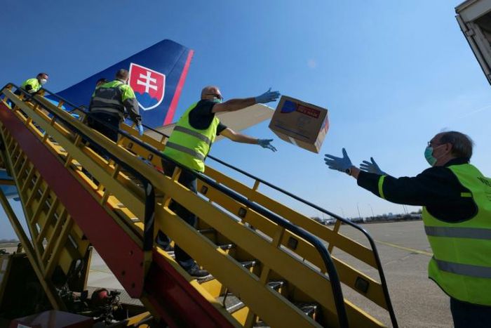 Police in Slovakia unload a plane after it touched down from China with testing kits and masks