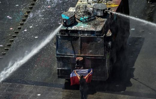A demonstrator stands in front of police water cannon in Santiago, Chile, which has been rocked by protests