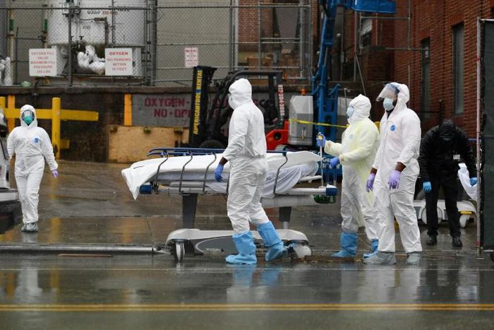 Medical personnel move a deceased patient to a refrigerated truck serving as a makeshift morgue in Brooklyn