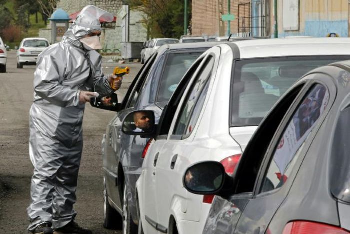 Members of the Iranian Red Crescent test people for coronavirus symptoms stopped on the Tehran to Alborz highway under a government order to screen every person for the illness
