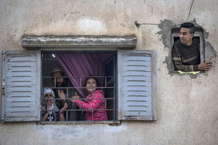 Moroccans confined at home thank the authorities from their windows as security forces and health workers instruct people to return to and remain at home as a measure against the COVID-19 coronavirus pandemic, in Rabat's district of Takadoum